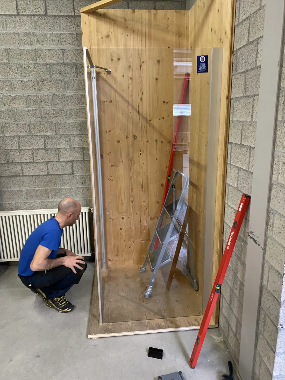 Un tecnico di Duschbad Expert monta una cabina doccia in legno e vetro